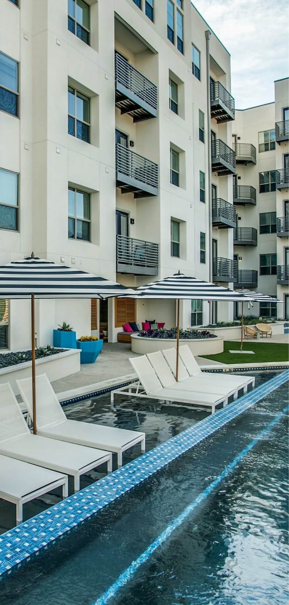 Exterior white apartment building with pool chairs