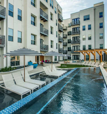 Exterior white apartment building with pool chairs